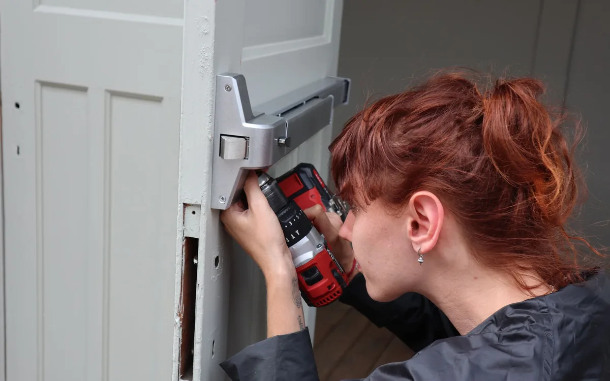 Handyman drilling a strike plate into a door frame